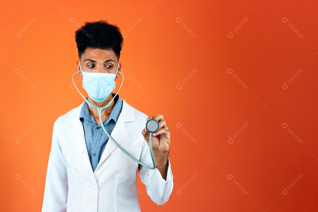 Médico brasileiro negro residente com estetoscópio e máscara pandêmica em fundo laranja.