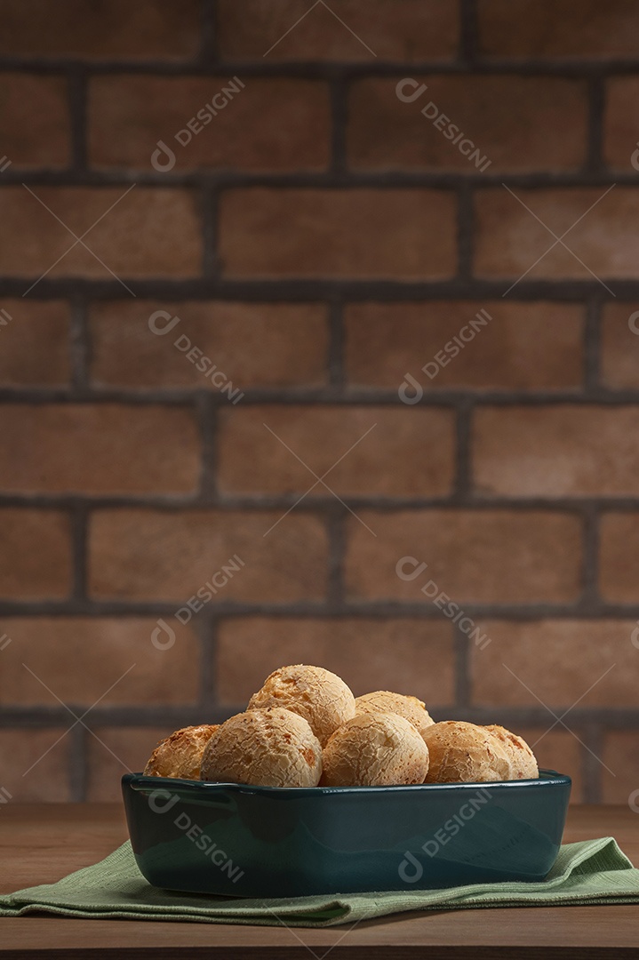 Pães de queijo em uma travessa em um fundo de parede de tijolos.