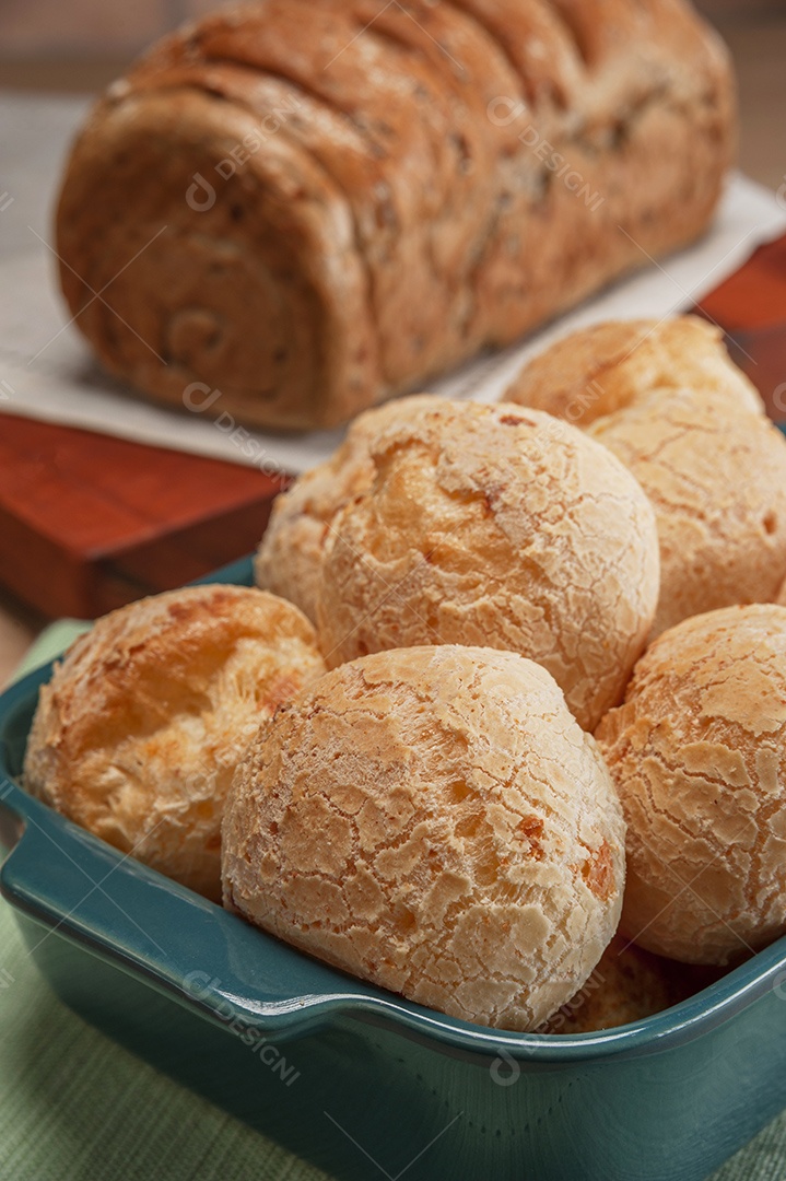 Pão integral com pães de queijo na cesta atrás.