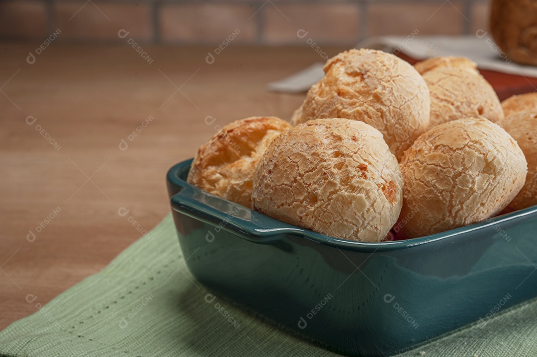 Pães de queijo em uma travessa na mesa de madeira.