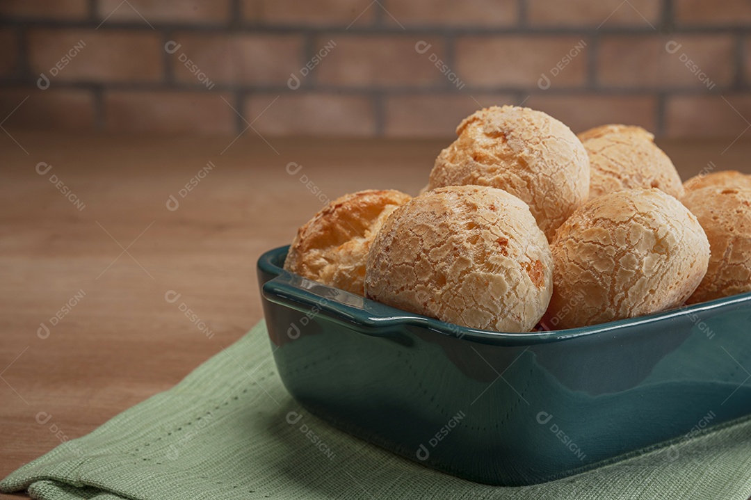 Pães de queijo em uma travessa na mesa de madeira.