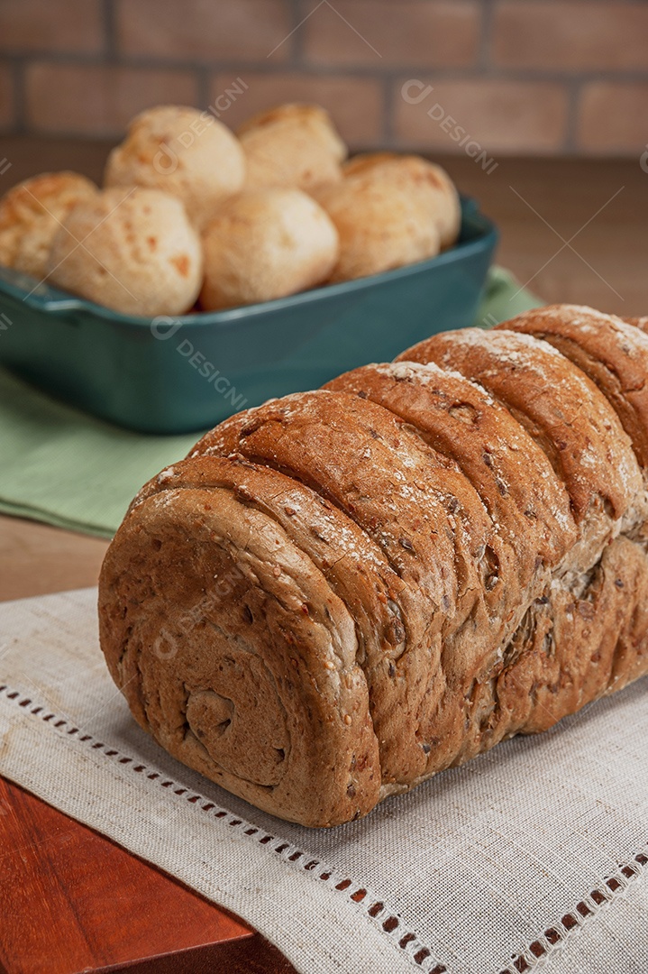Pão integral com pães de queijo na cesta atrás.