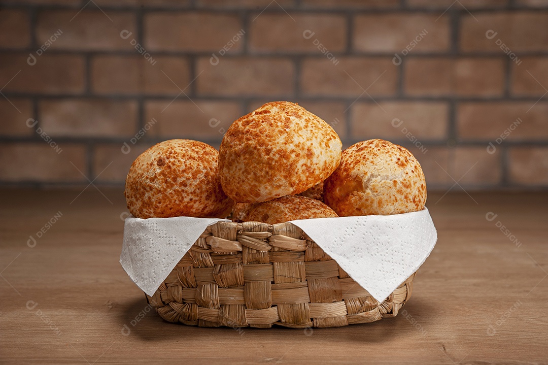 Pães de queijo em uma cesta na mesa de madeira e fundo da parede de tijolos.