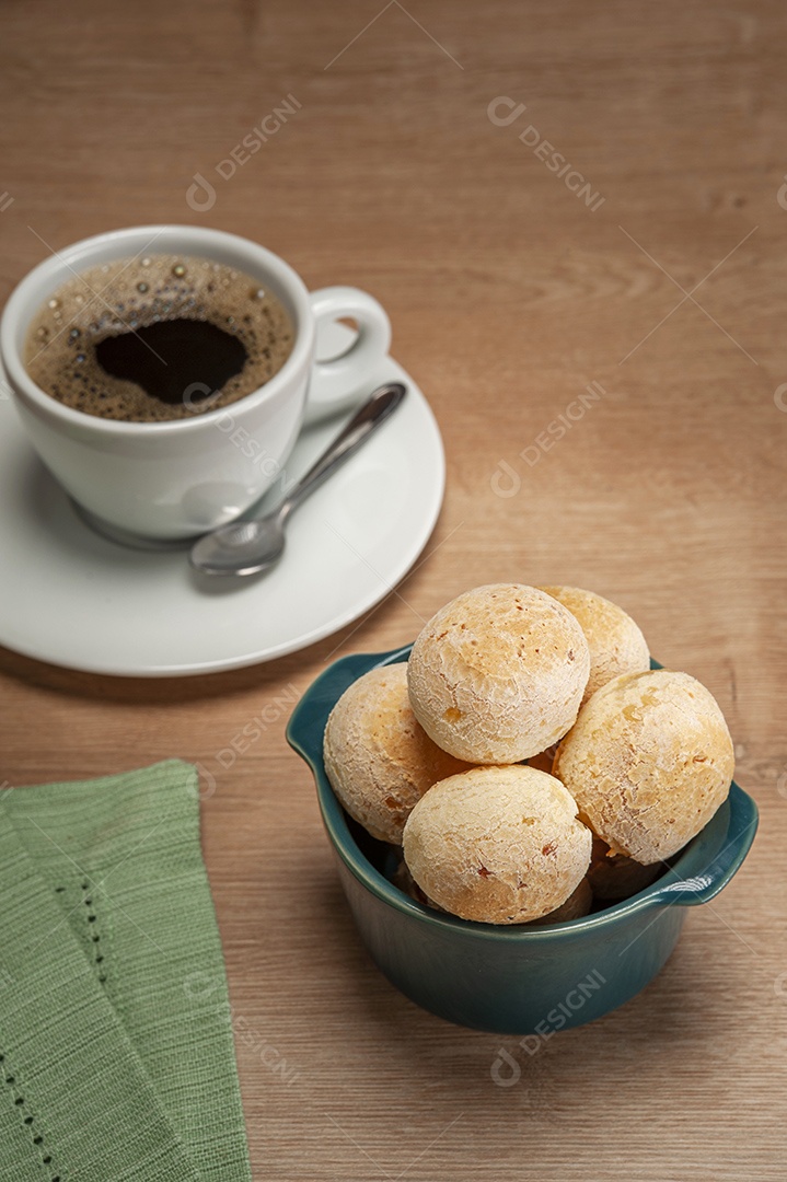 Pães de queijo em um ramekin verde na mesa de madeira e fundo da parede de tijolos.