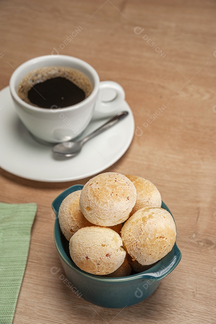 Pães de queijo em um ramekin verde na mesa de madeira e fundo da parede de tijolos.