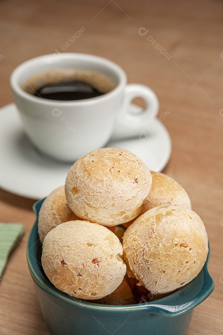 Pães de queijo em um ramekin verde na mesa de madeira e fundo da parede de tijolos.