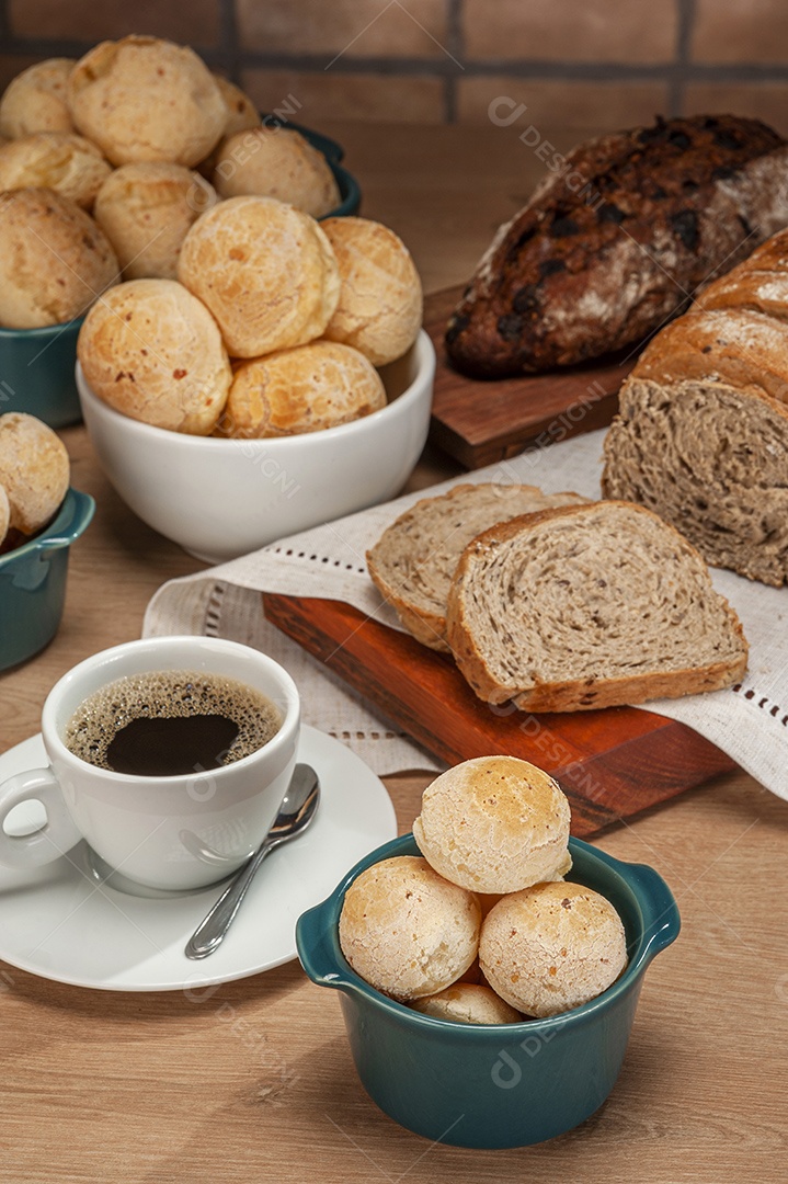 Pães de queijo em um ramekin verde com uma xícara de café na mesa de madeira e fundo de parede de tijolos.
