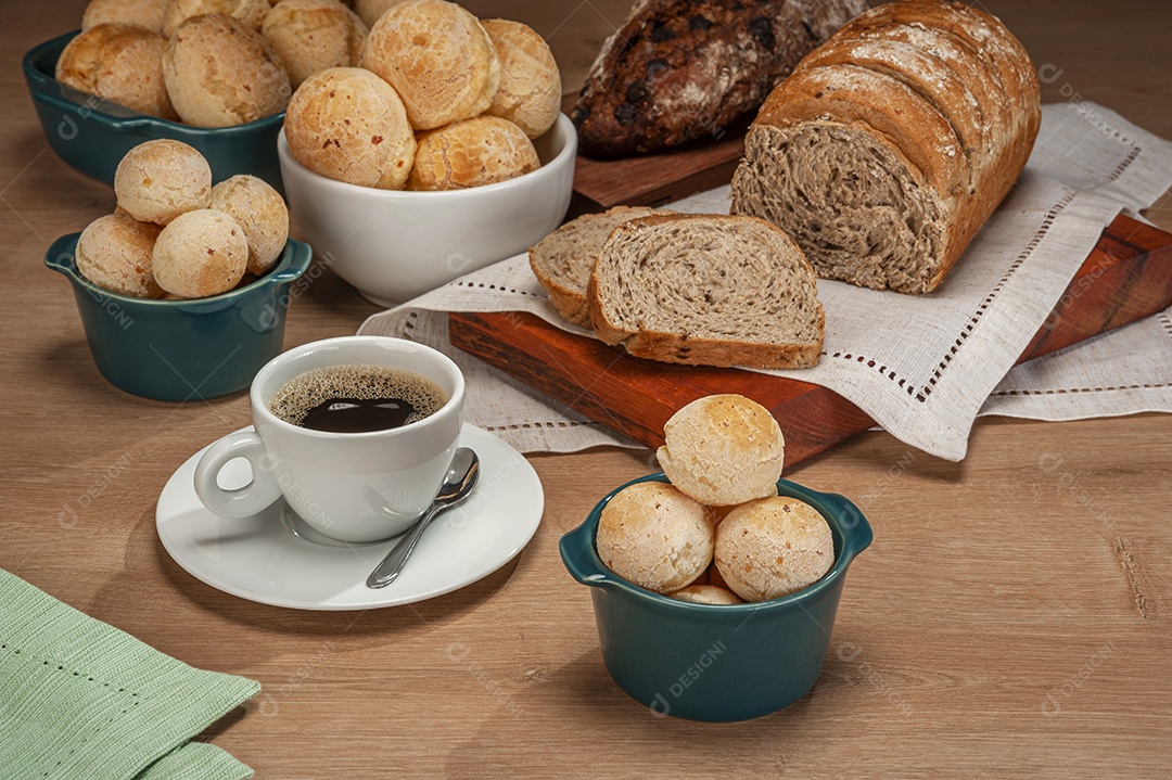 Pães de queijo em um ramekin verde com uma xícara de café na mesa de madeira e fundo de parede de tijolos.