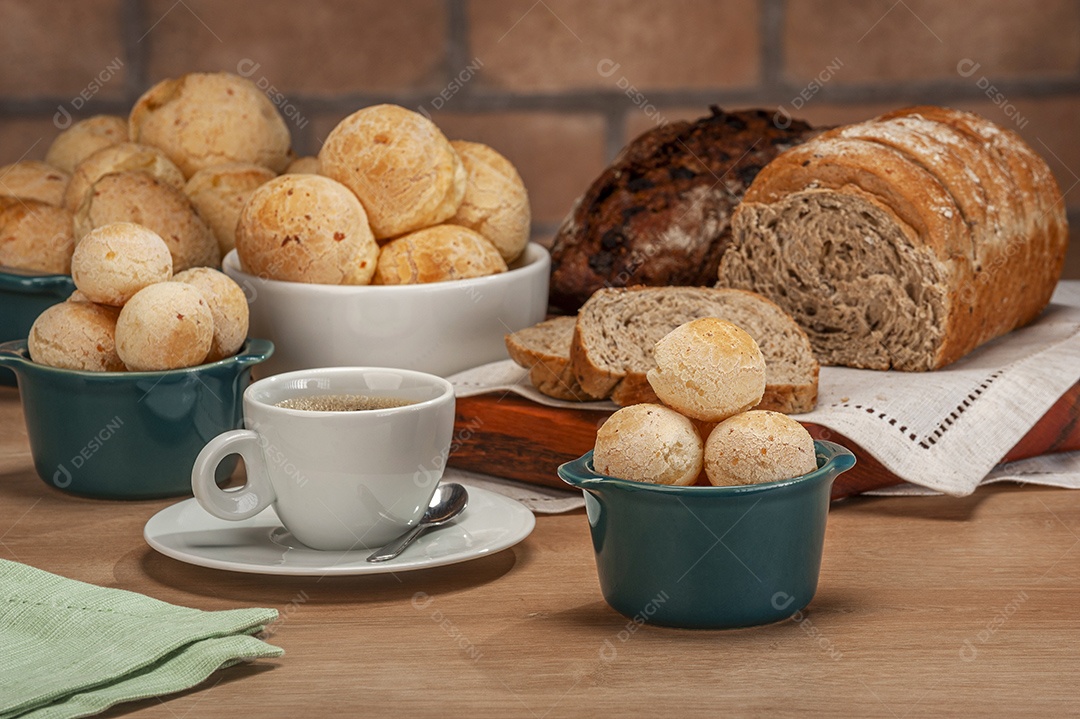 Pães de queijo em um ramekin verde com uma xícara de café na mesa de madeira e fundo de parede de tijolos.