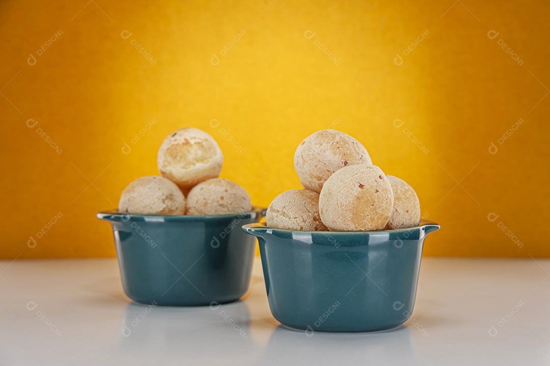 Pães de queijo em um ramekin verde na mesa de madeira e fundo da parede de tijolos.
