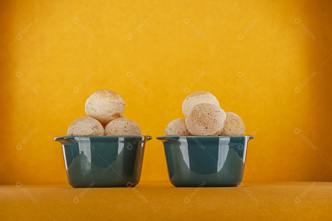 Pães de queijo em um ramekin verde na mesa de madeira e fundo da parede de tijolos.