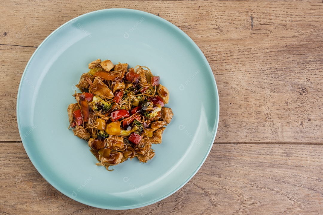 Yakisoba com carne de frango em prato verde na mesa de madeira - vista superior
