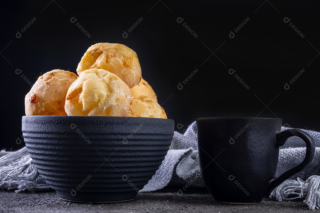 Deliciosos pães de queijo e uma caneca de café em fundo escuro