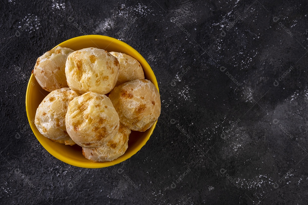 Tigela amarela com pães de queijo em fundo escuro