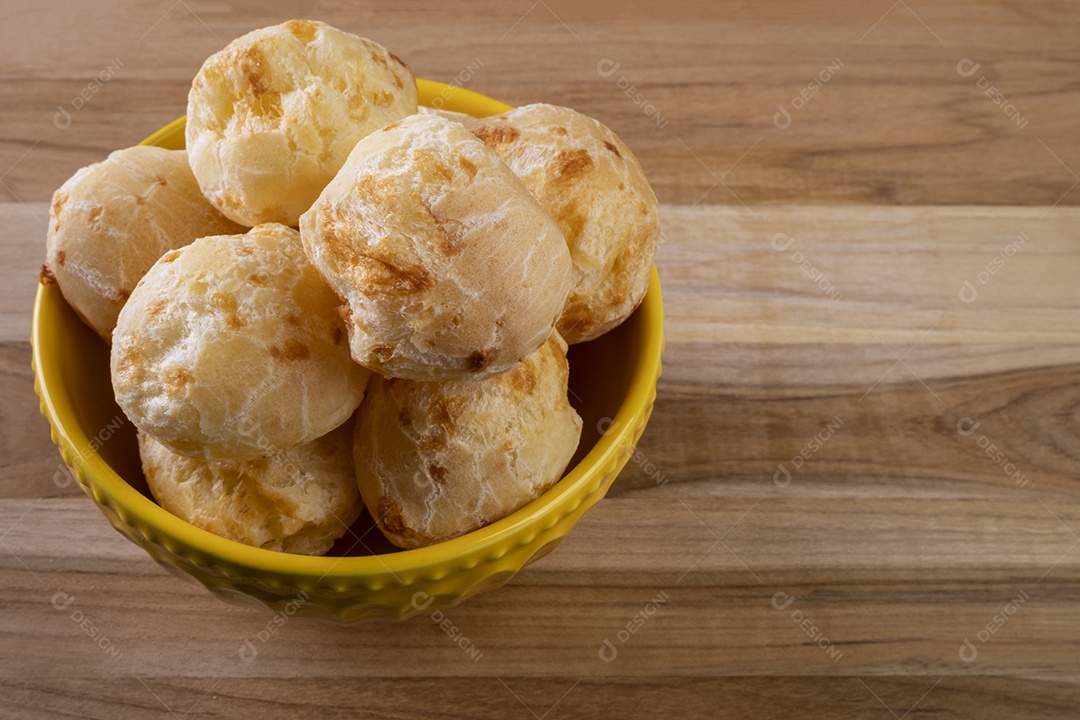 Tigela com pães de queijo na mesa de madeira