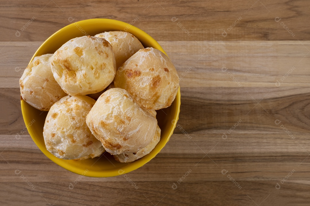 Tigela com pães de queijo na mesa de madeira