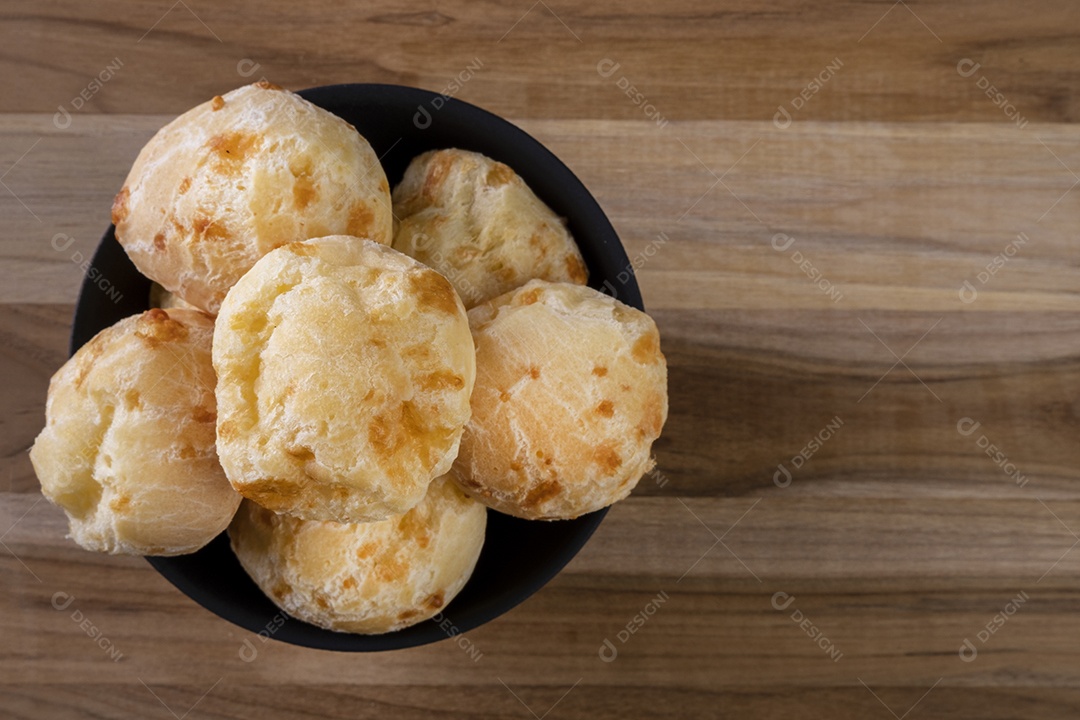 Tigela com pães de queijo na mesa de madeira