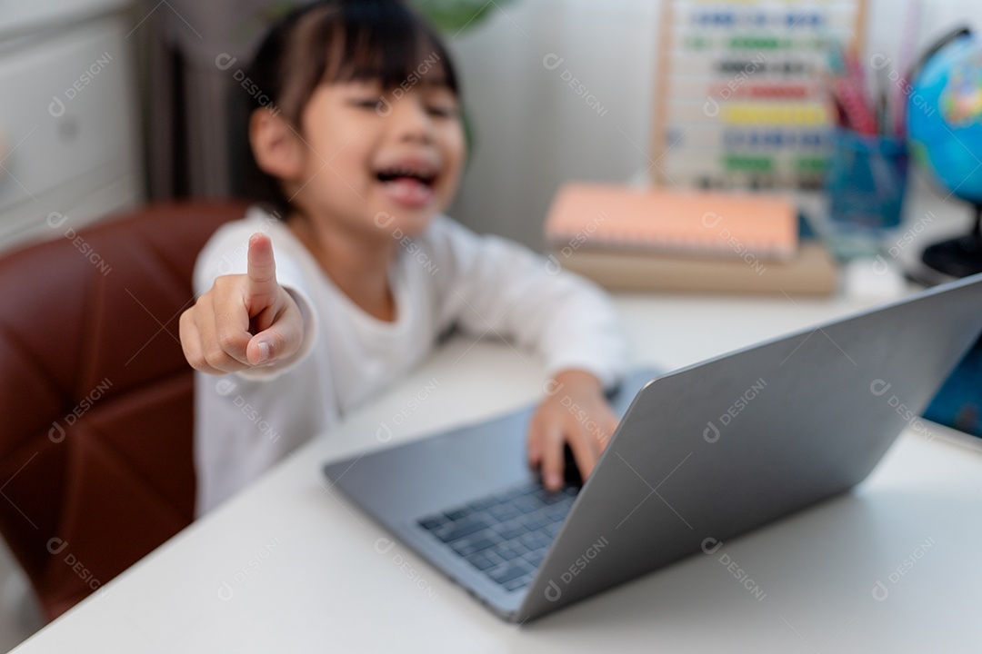 Aluna asiática fazendo sua lição de casa com o laptop em casa. As crianças usam aparelhos para estudar. Educação e ensino a distância para crianças. Educação domiciliar durante a quarentena. Ficar em casa