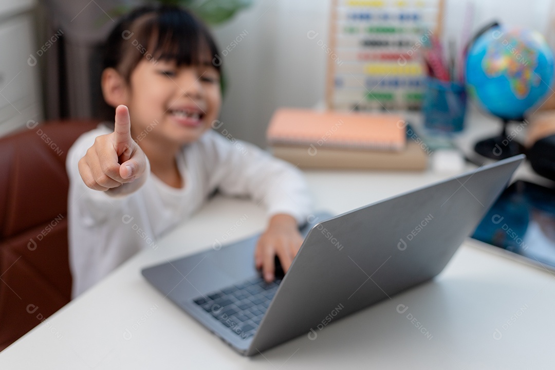 Aluna asiática fazendo sua lição de casa com o laptop em casa. As crianças usam aparelhos para estudar. Educação e ensino a distância para crianças. Educação domiciliar durante a quarentena. Ficar em casa