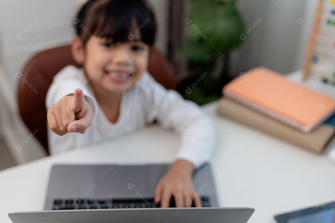 Aluna asiática fazendo sua lição de casa com o laptop em casa. As crianças usam aparelhos para estudar. Educação e ensino a distância para crianças. Educação domiciliar durante a quarentena. Ficar em casa