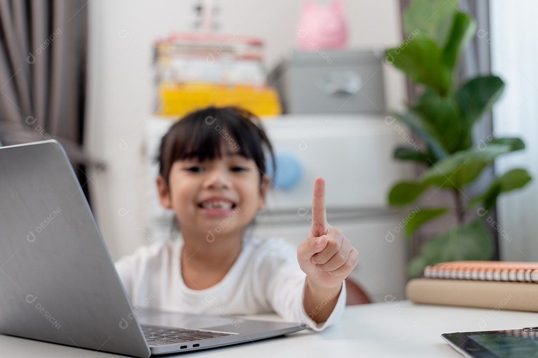 Aluna asiática fazendo sua lição de casa com o laptop em casa. As crianças usam aparelhos para estudar. Educação e ensino a distância para crianças. Educação domiciliar durante a quarentena. Ficar em casa