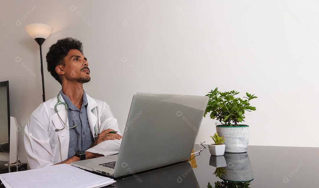 Jovem fazendo home office durante o dia na mesa com laptop, tablet e celular