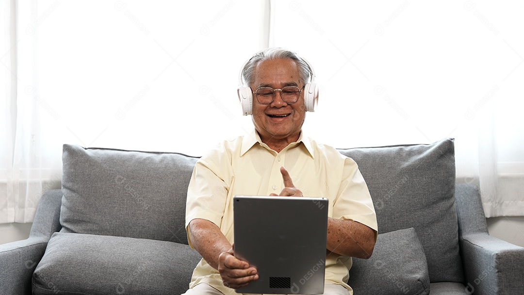 Sorriso de avô masculino idoso sênior com fones de ouvido relaxantes de óculos está ouvindo música usando um tablet digital