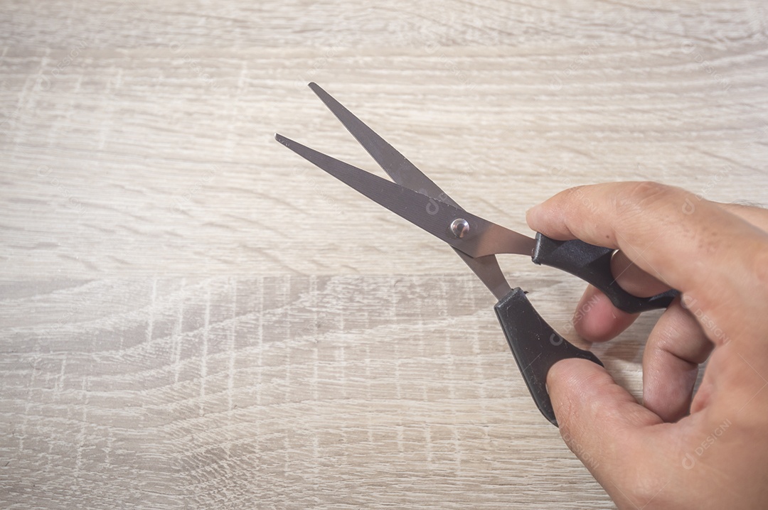 Mão segurando uma tesoura, fundo branco de madeira, foto para recorte.