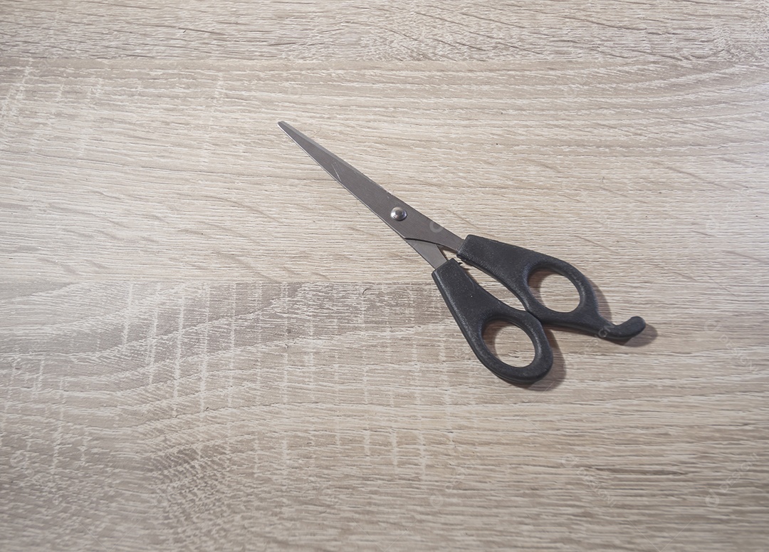 Mão segurando uma tesora, fundo branco de madeira, foto para recorte.