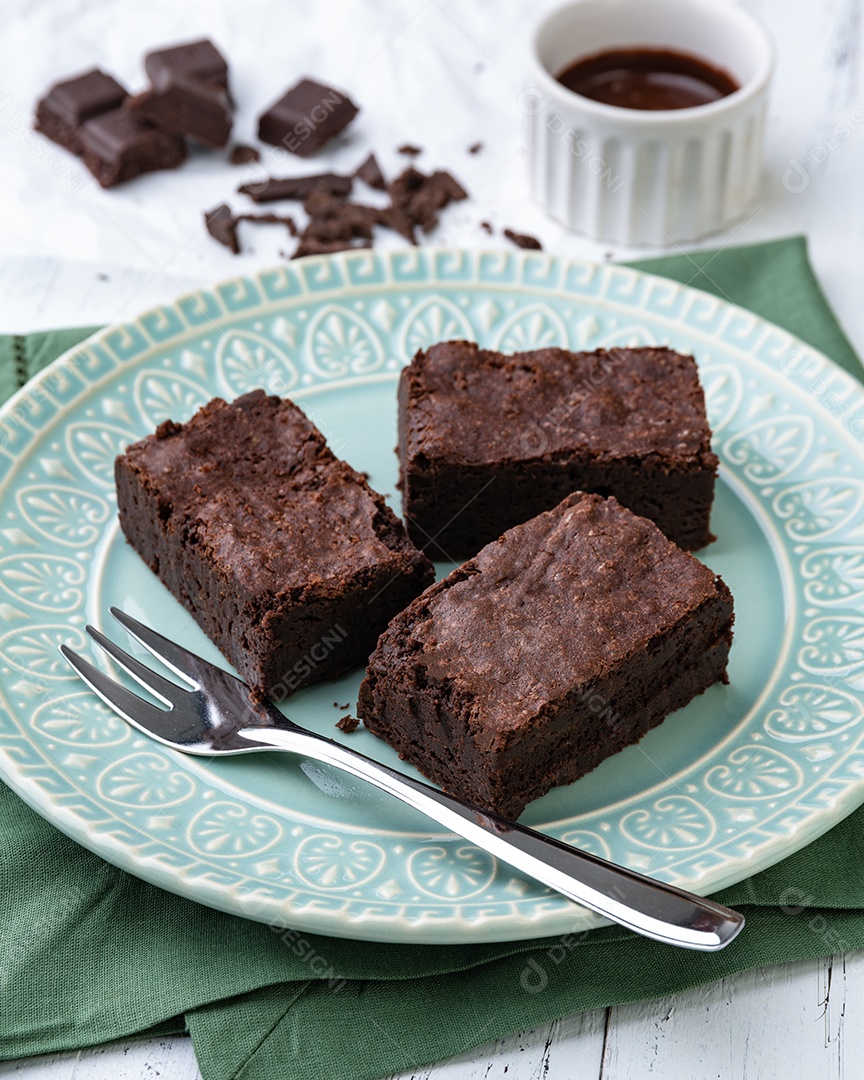 Brownies em um prato verde sobre a mesa de madeira branca.