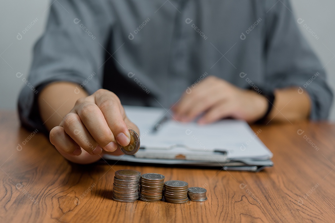 Homem colocando moedas no conceito de pilha de dinheiro economizando dinheiro para contabilidade financeira.