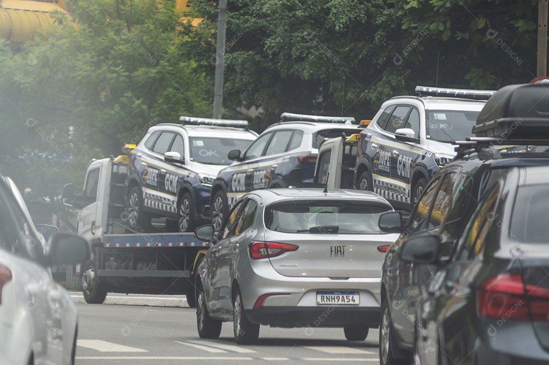 Carros de polícia no trânsito sendo transportados por um guincho.