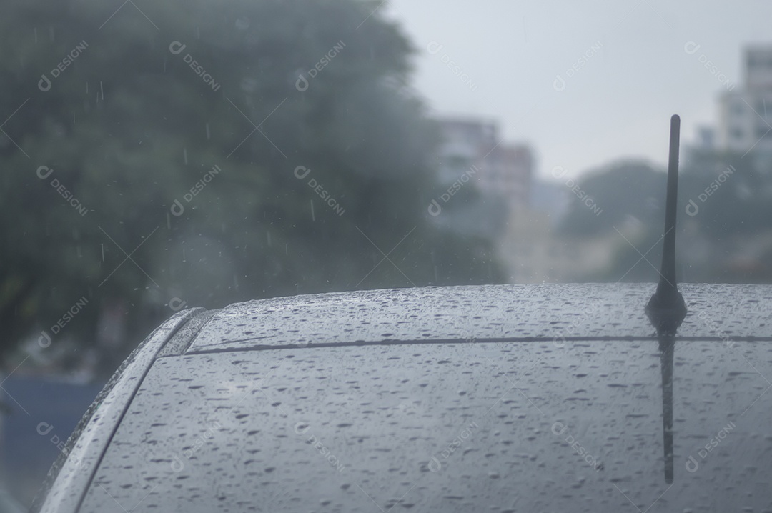 Telhado de um carro com antena a vista em um dia chuvoso com espaço para texto à esquerda.