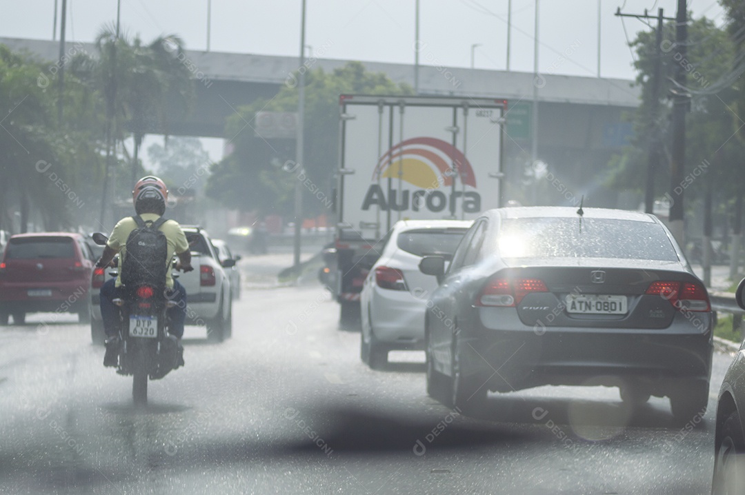 Caminhão da marca brasileira aurora passando por uma avenida em um dia chuvoso.