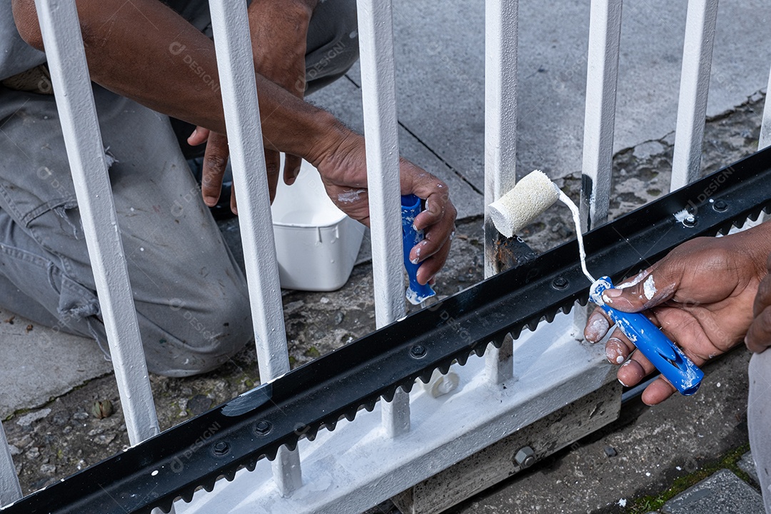 Mão dos pintores retocando o portão elétrico da garagem do condomínio.