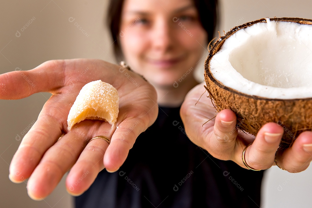 Menina segurando doce de coco e coco nas mãos