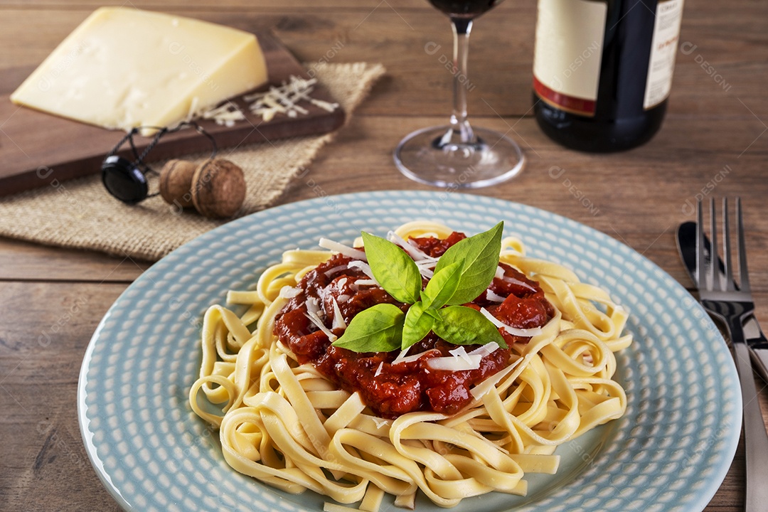 Prato com macarrão coberto com molho de tomate, com um copo