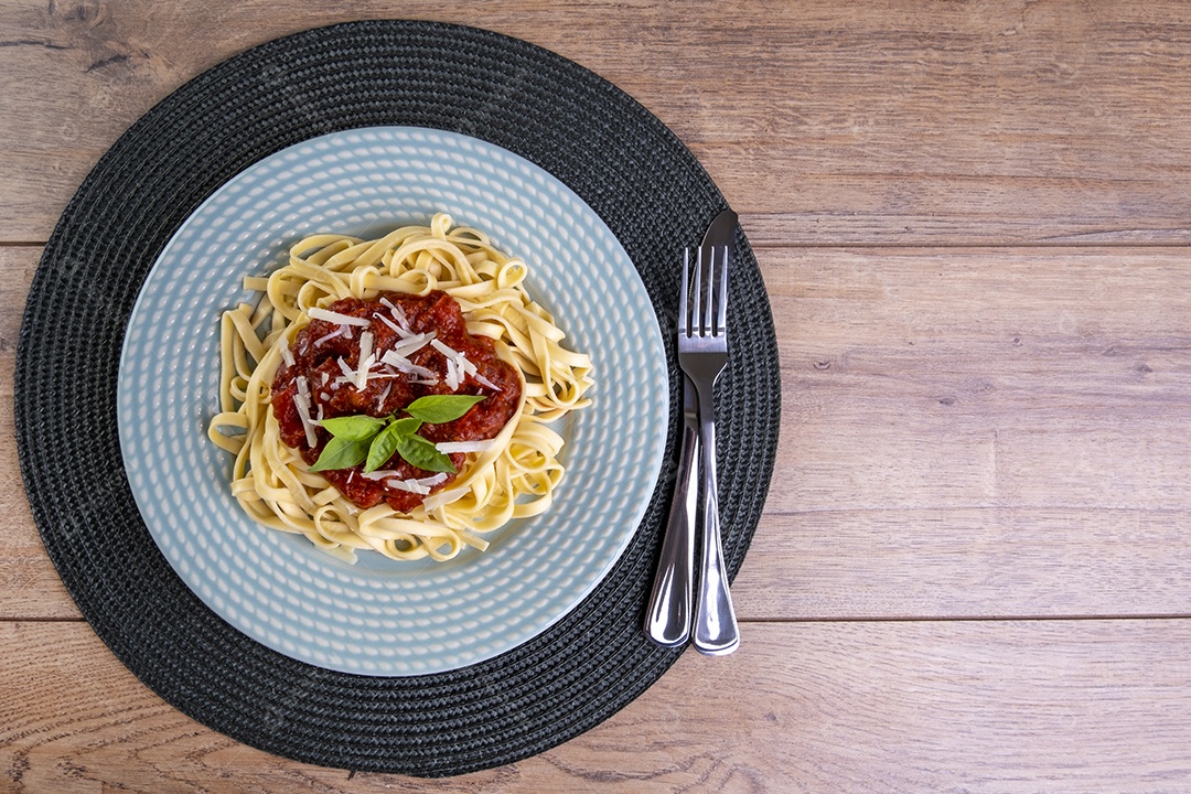 Prato com macarrão coberto com molho de tomate, com um copo