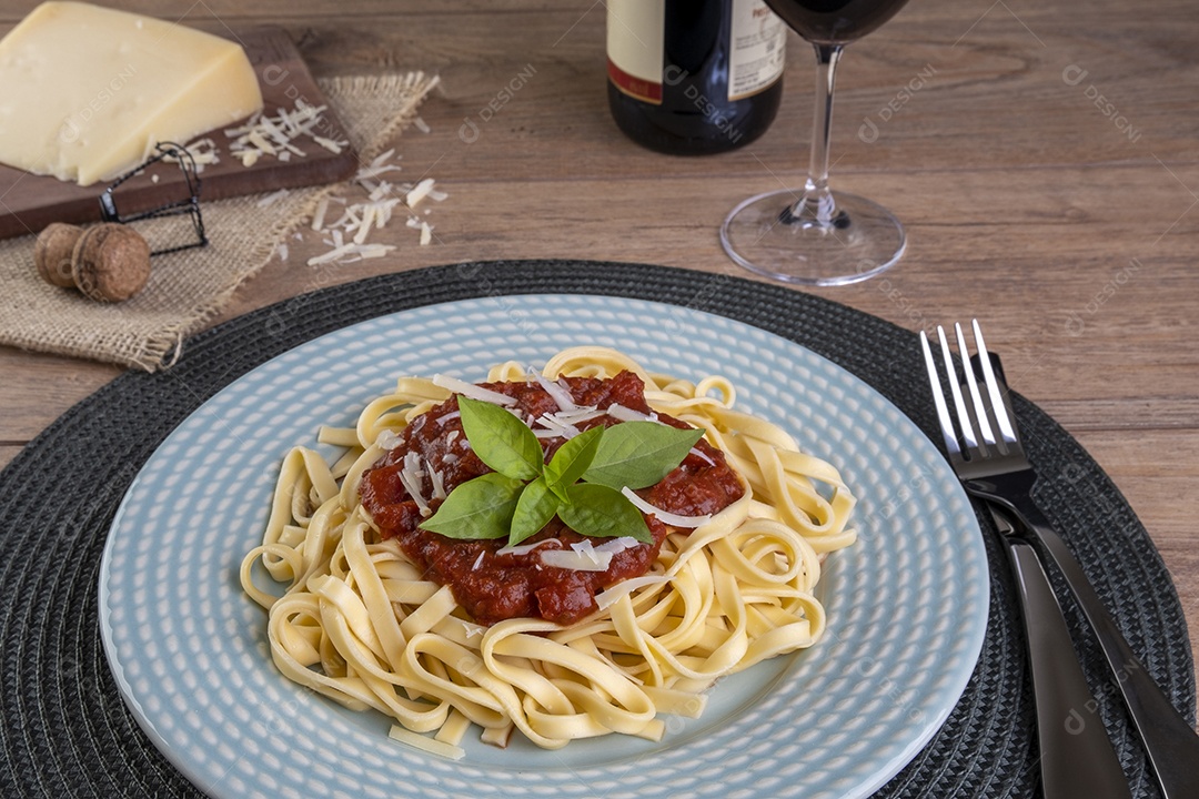 Prato com macarrão coberto com molho de tomate, com um copo