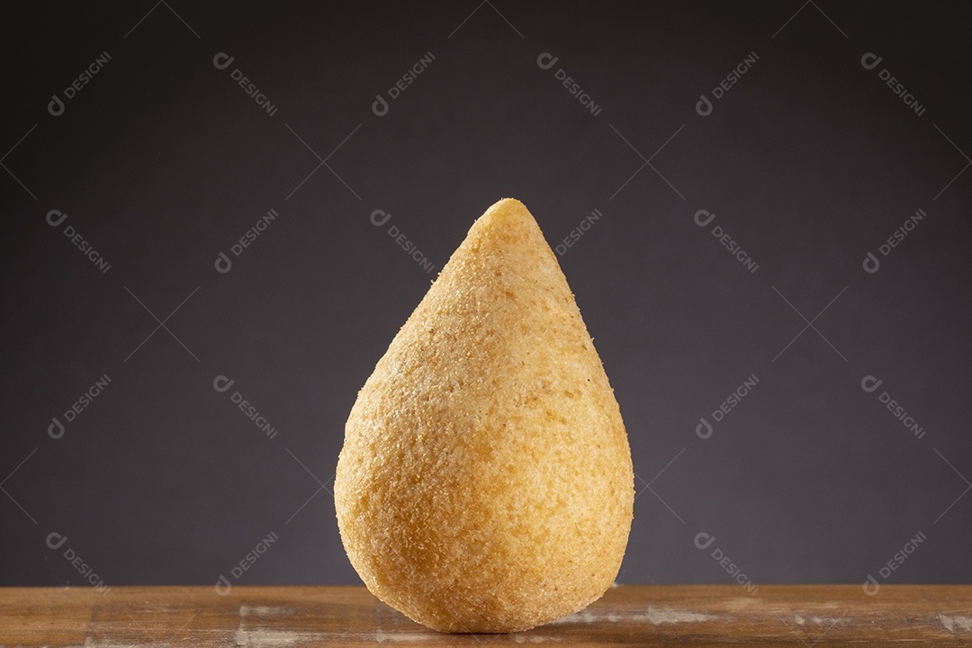 Coxinha frita na mesa de madeira com fundo gradiente marrom