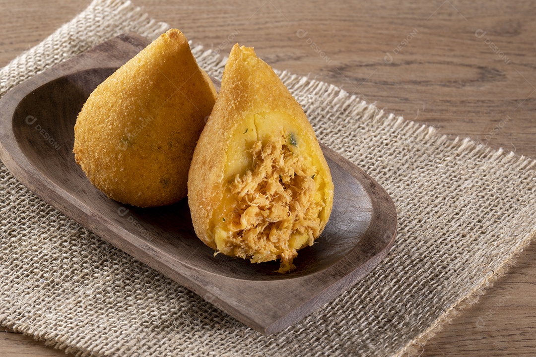 Coxinha frita em recipiente de madeira na mesa de madeira