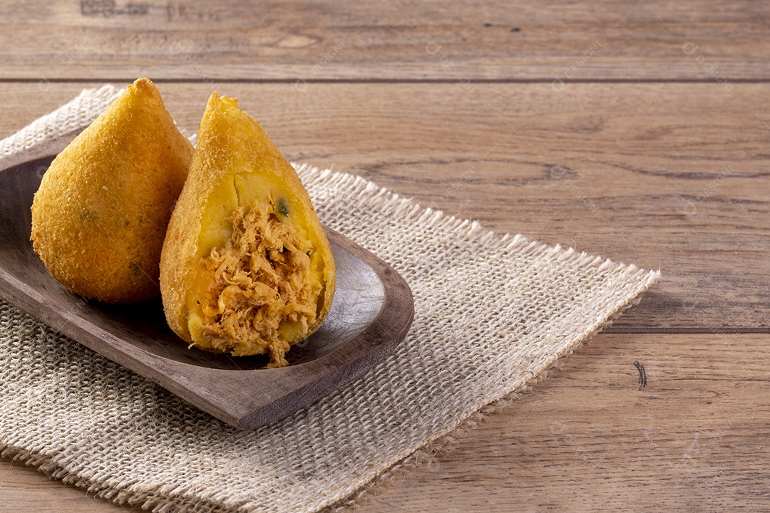 Coxinha frita em recipiente de madeira na mesa de madeira