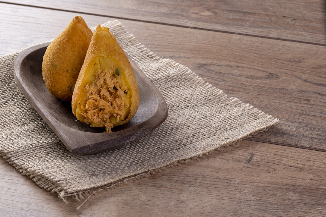 Coxinha frita em recipiente de madeira na mesa de madeira