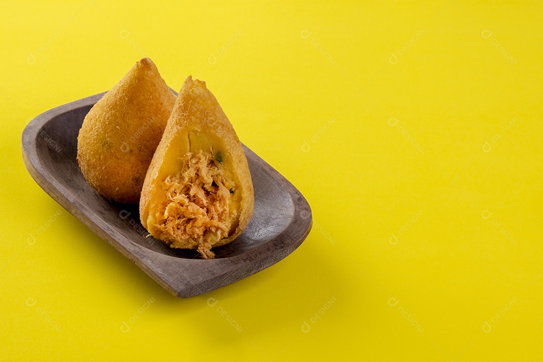 Coxinha frita em recipiente de madeira na mesa de madeira