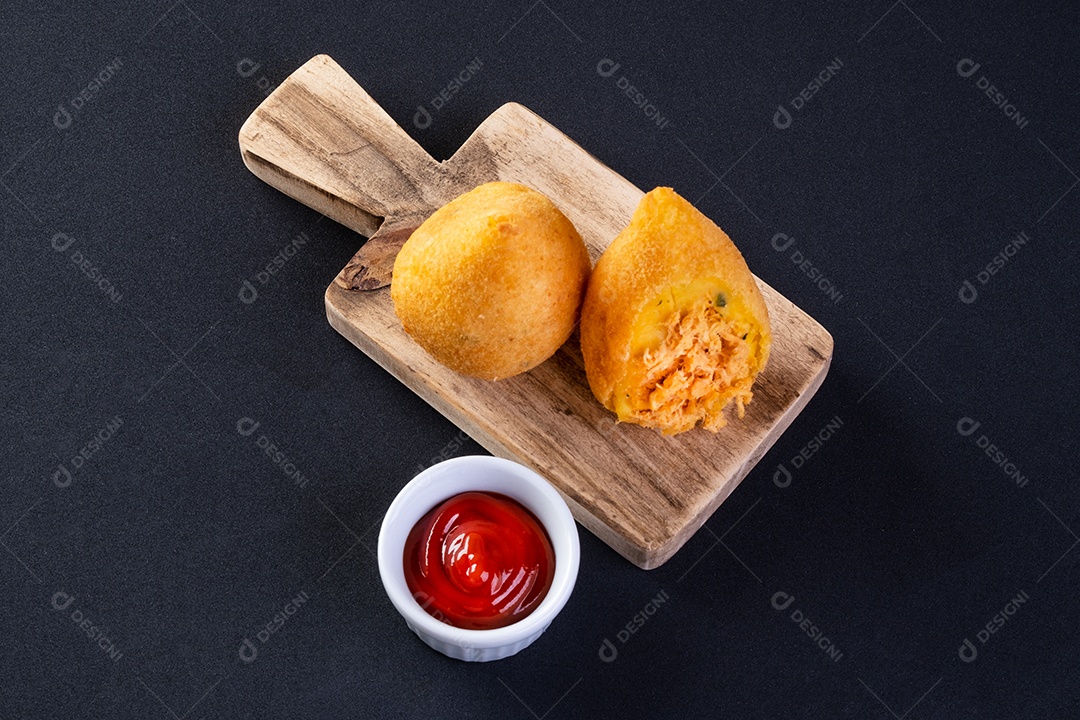 Coxinha na placa de madeira com fundo preto