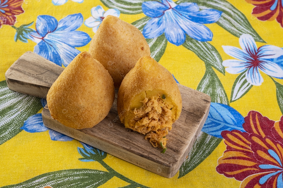 Coxinha frita na tábua de corte em tecido com estampas de flores