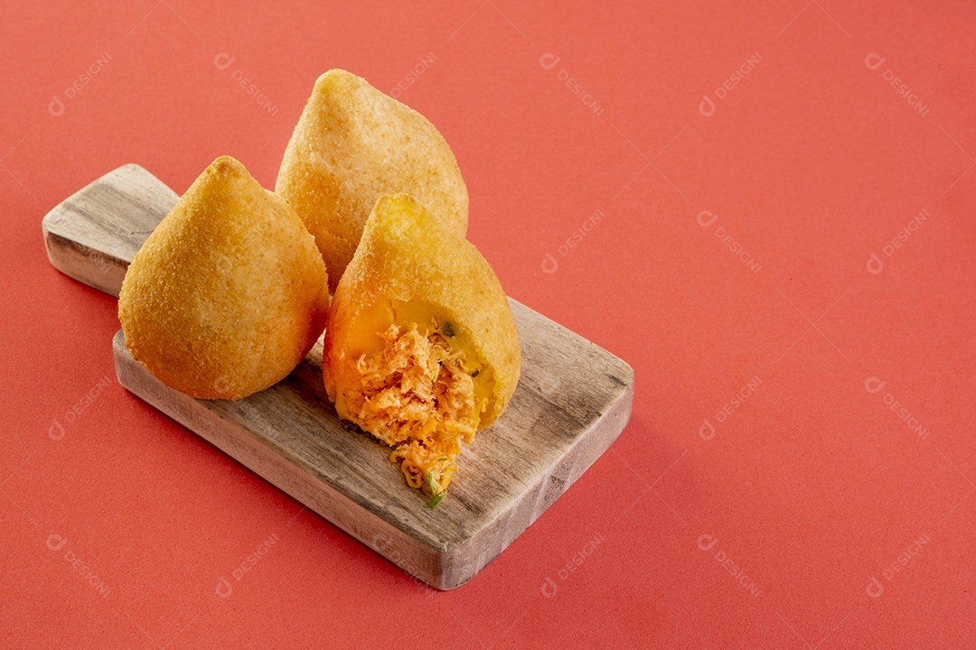 Coxinha na placa de madeira com fundo vermelho