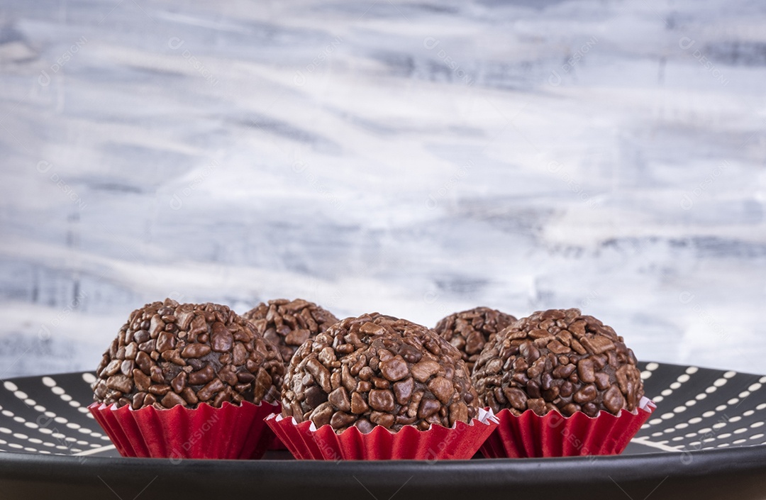 Placa preta com brigadeiros na mesa de madeira