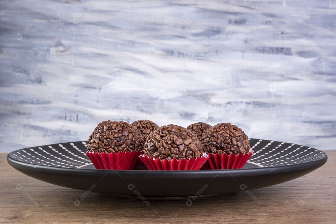 Placa preta com brigadeiros na mesa de madeira