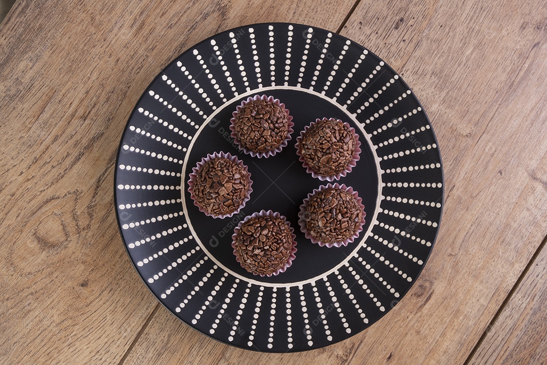 Placa preta com brigadeiros na mesa de madeira